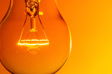 Close up glowing light bulb on orange background