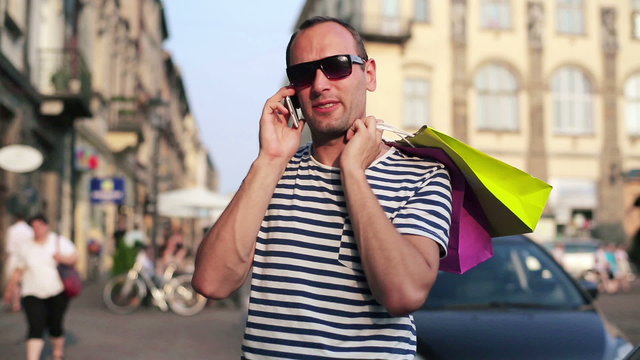 Man with shopping bags talking on cellphone in the city