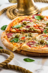 Closeup of Fresh pizza with salami, olives and basil