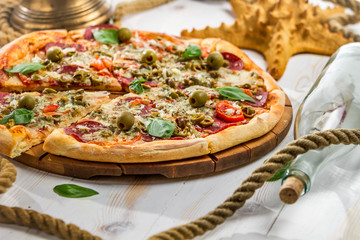 Fresh pizza on a boat made of salami and olives