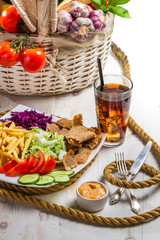 Vegetables, fries and meat kebab served with cold Coke