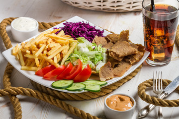 Closeup of vegetables, fries and meat kebab on a plate