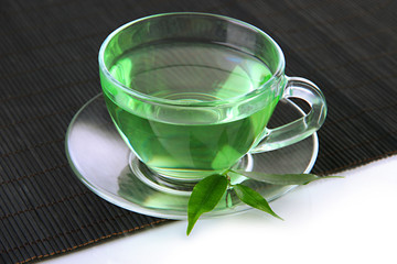 Transparent cup of green tea on bamboo mat, isolated on white