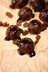 Chocolate candies and coffee beans, on beige paper background