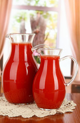 Tomato juice in pitchers on table in room