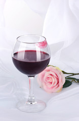 Glass of wine with lipstick imprint on white fabric background