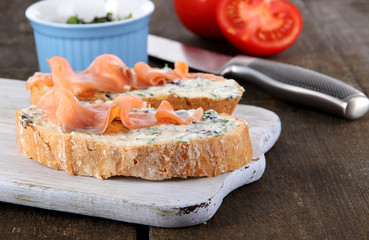 Fish sandwiches on cutting board on wooden table