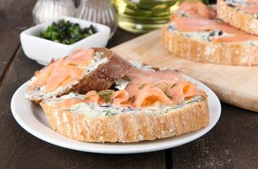 Fish sandwiches on cutting board and plate on wooden table