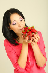 Beautiful young woman with strawberries on grey background