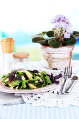 Light salad on plate on table on room background