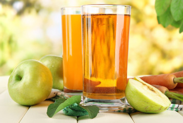 Glasses of juice, apples and carrots