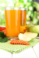 Glasses of juice, apples and carrots