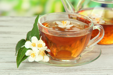 Cup of tea with jasmine, on wooden table, on bright background