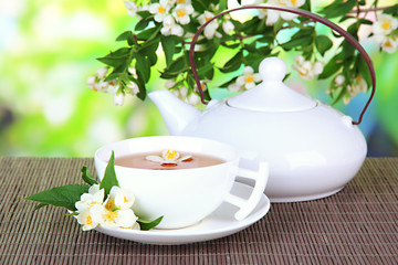 Cup of tea with jasmine, on bamboo mat, on bright background