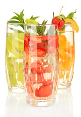 Glasses of fruit drinks with ice cubes isolated on white