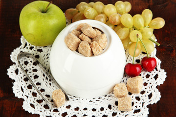 Unrefined sugar in white sugar bowl on wooden background