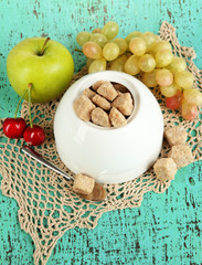 Unrefined sugar in white sugar bowl on wooden background