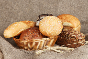 Baked bread in wicker basket on burlap background
