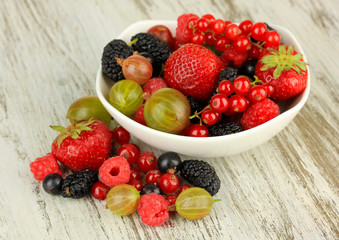 Ripe berries in bowl on table close-up