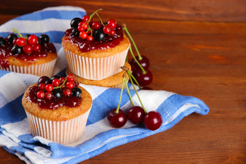 Tasty muffins with berries on wooden table