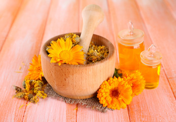 Medicine bottles and calendula flowers on wooden background