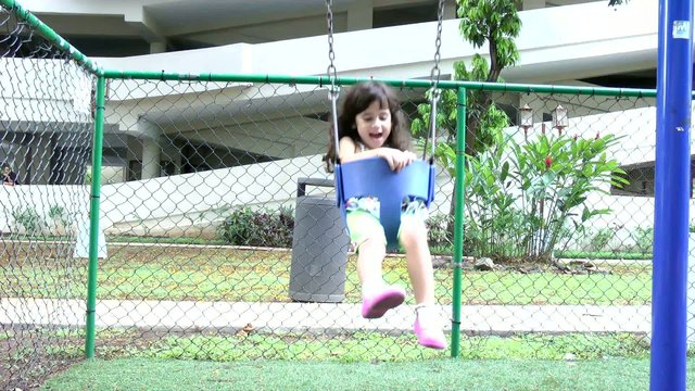 slow motion, a little girl swings on a swing set