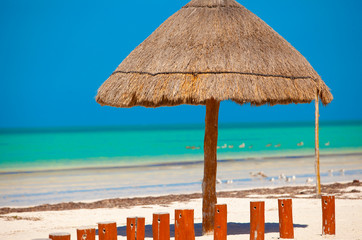 Big straw umbrella at the white sand beach