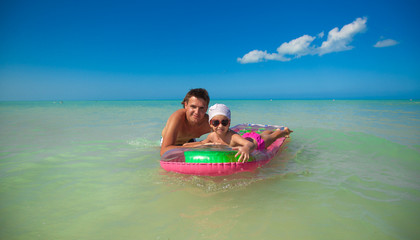 Obraz premium Young father with young daughter on an air mattress in the sea