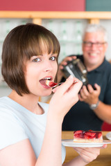 junge frau mit erdbeerkuchen im cafe