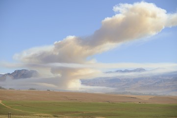 Naklejka premium Smoke from a grass fire in the Drakensberg Foothills
