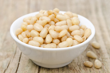 pine nuts in a bowl on wooden background close-up