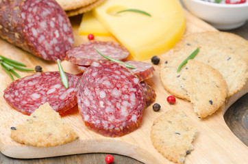 salami, cheese, crackers and spices on a cutting board