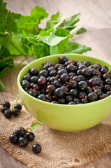 black currants in a bowl on wooden background
