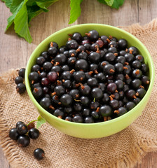 black currants in a bowl on wooden background