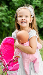 Cute little girl with her toy carriage and doll