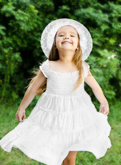 Portrait of adorable smiling little girl in white dress and hat