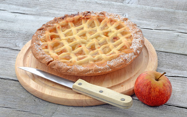 Apple pie on  cutting board with knife and apple