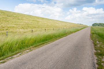 Obraz premium Seemingly endless road along an embankment and a fence