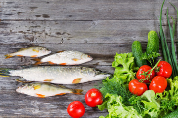 river fish with vegetables on wooden background