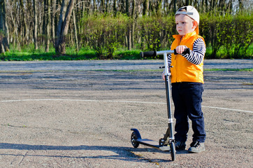 Handsome little boy holding his scooter