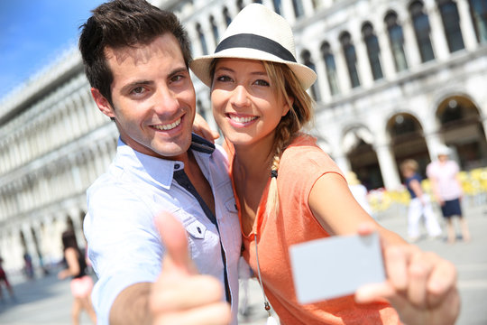 Cheerful couple showing tourist pass in Piazza San Marco