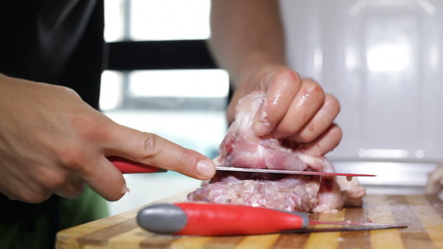 Closeup of a man cutting raw chicken