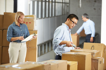 Workers Checking Goods On Belt In Distribution Warehouse