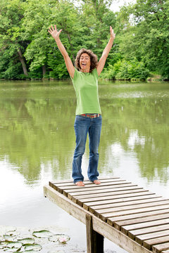 Glückliche lebensfrohe Frau am idyllischen Teich