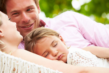 Obraz na płótnie Canvas Family Relaxing In Beach Hammock With Sleeping Daughter