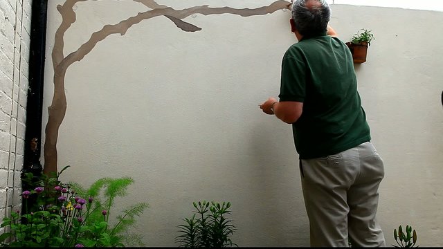 man painting vine on wall