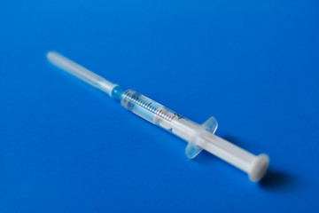 Syringe with medication on blue background