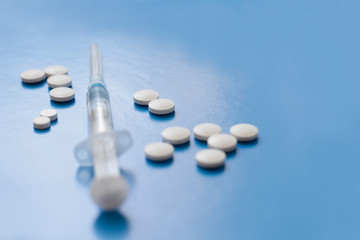 Syringe and pills on blue background