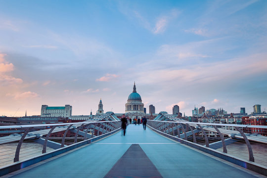 Fototapeta People walking over Millennium bridge at dusk. 