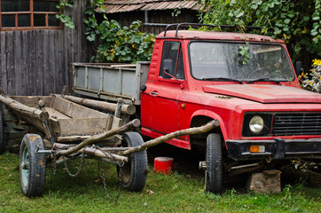 Obraz premium Old car and rustic carriage abandoned in a countryside yard
